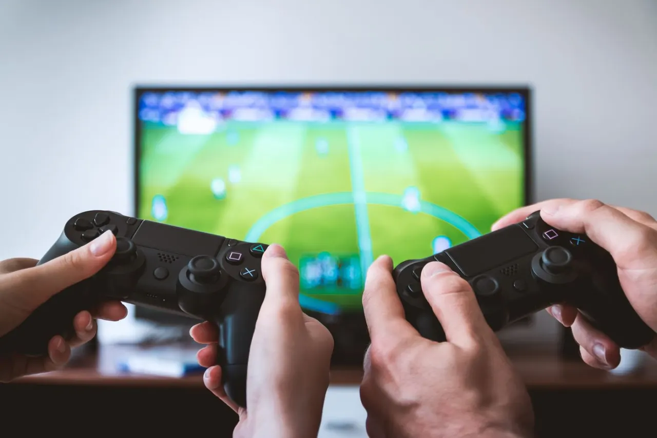 Person holding a game controller as a reminder that casual sports fans can choose a low-pressure role
