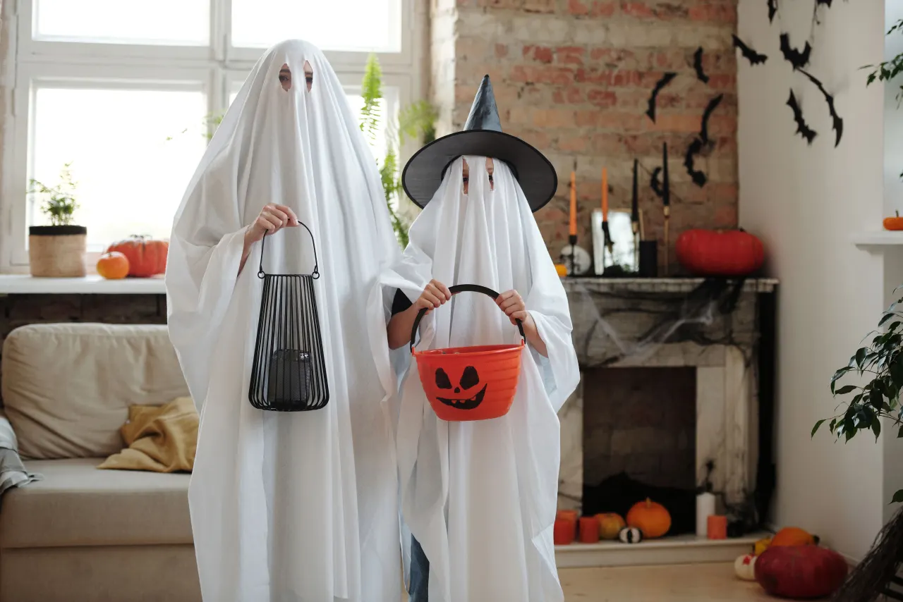People in ghost costumes inside a decorated room for capybara Halloween decorations
