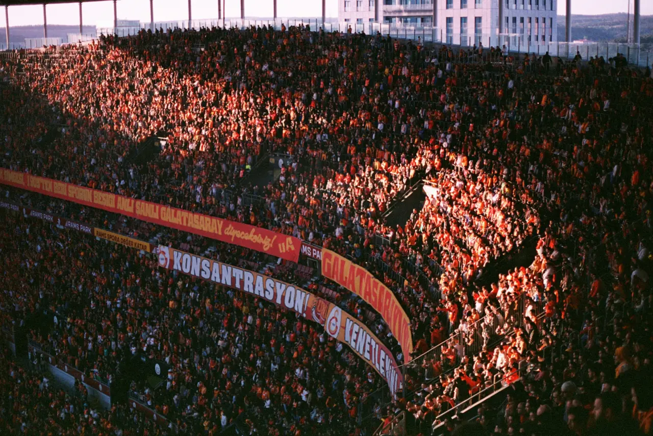 Packed soccer stadium crowd under bright floodlights during a large international match at night