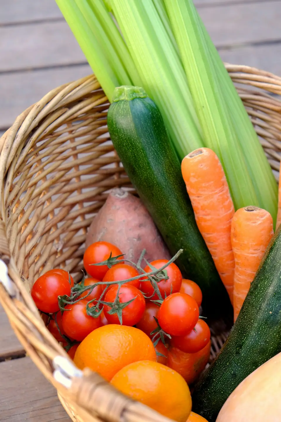 Basket of carrots and cucumbers in a garden