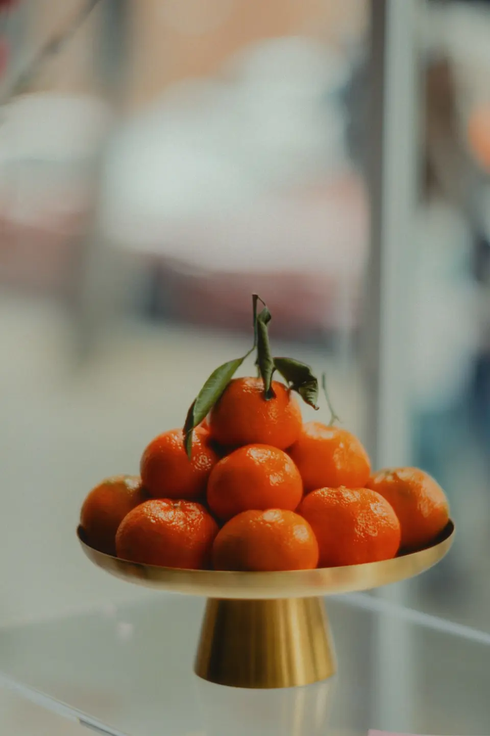 Whole tangerines with leaves arranged in a golden bowl